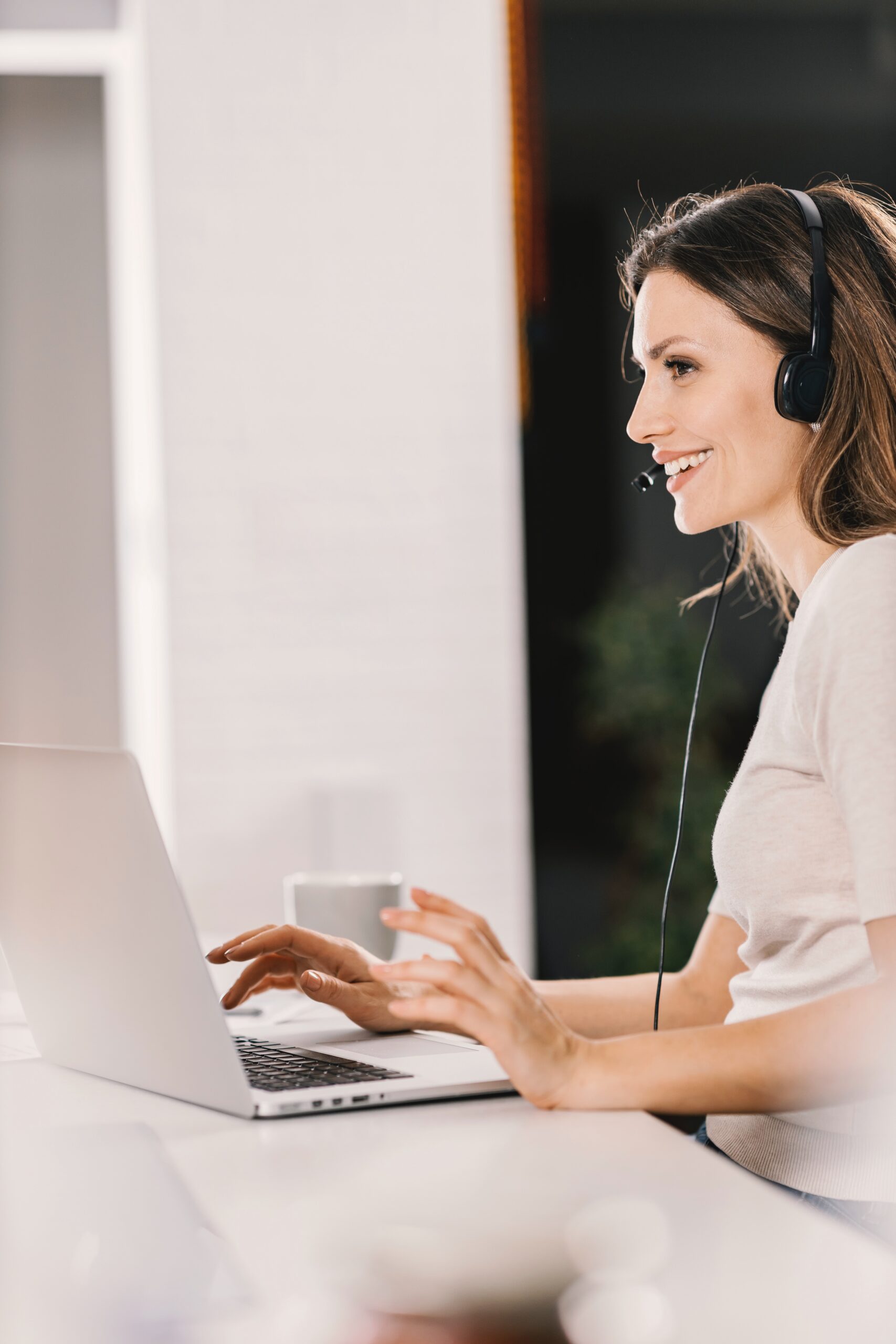 Una mujer sonríe y atiende una llamada telefónica, representando el servicio al cliente.