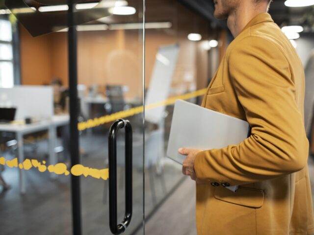 Hombre señalando un portátil cerrado, representando la garantía de confidencialidad de la información en la empresa.