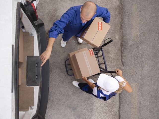 Dos repartidores de servicio de delivery llevando cajas de pedidos